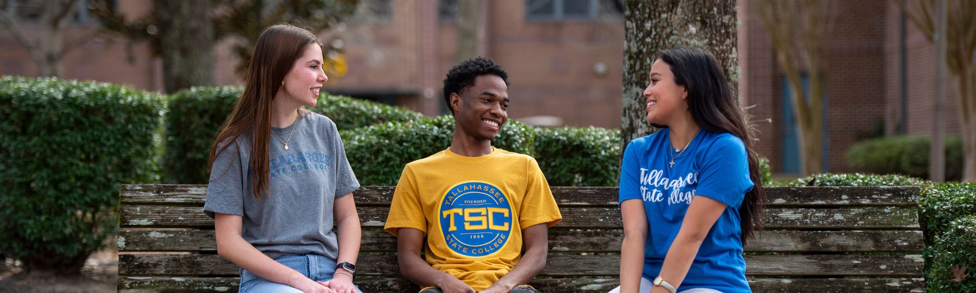 Three TSC students sitting on a bench and chatting.