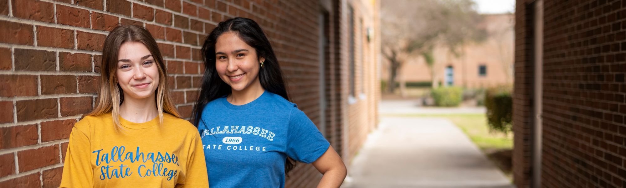 Two TSC students posed next to a brick wall.