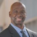 Man Wearing black blazer and blue shirt smiling